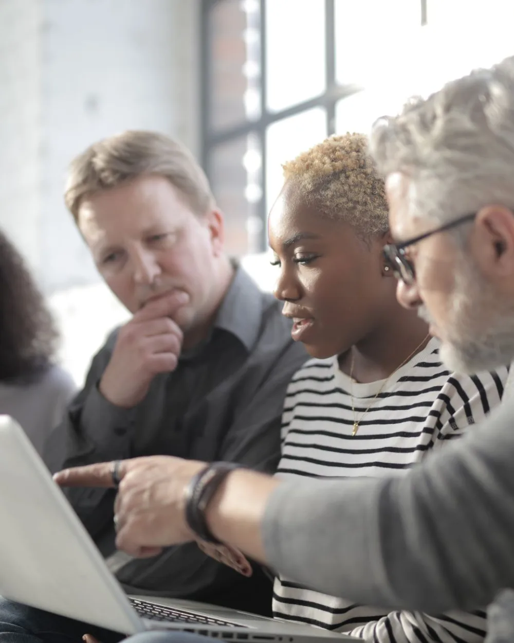 A diverse nonprofit team collaborating around a laptop in a bright office